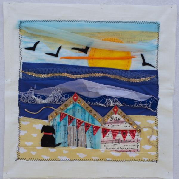 Quilt square showing a beach hut scene made from fabric and felt.