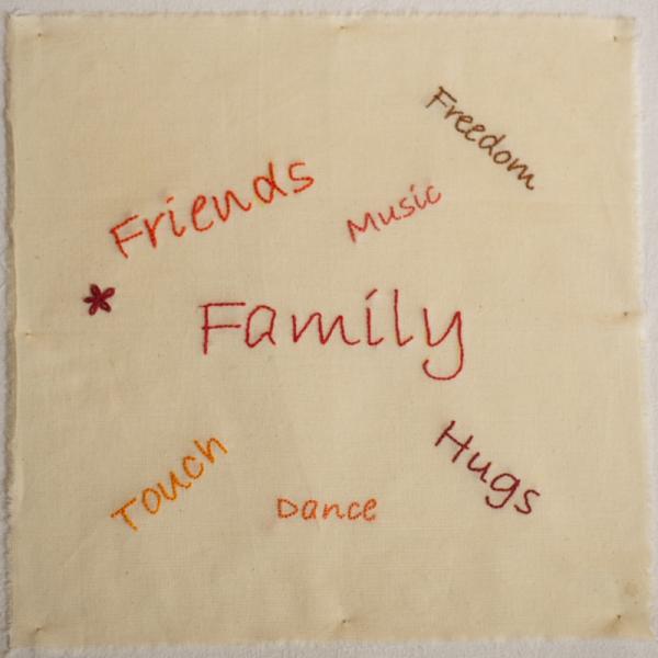 Quilt square with embroidered text saying Friends, Family, Freedom, Music, Touch, Dance and Hugs.