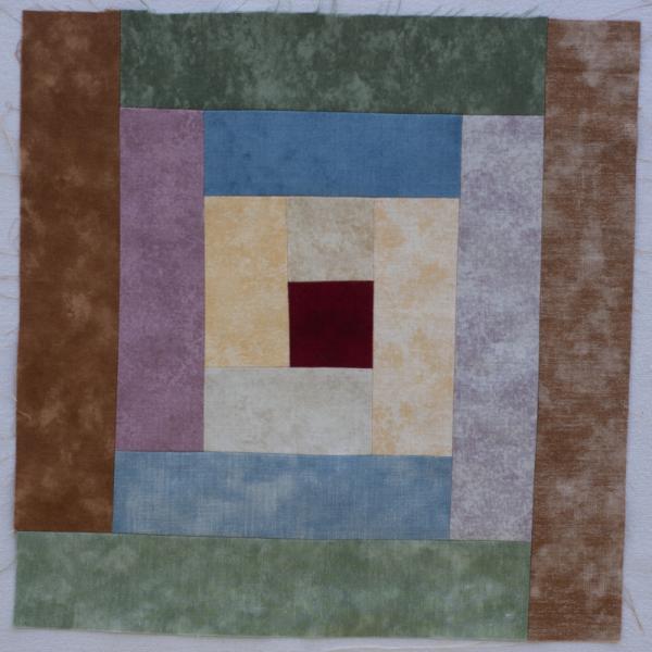Quilt square showing a patchwork design of concentric squares using different fabric.