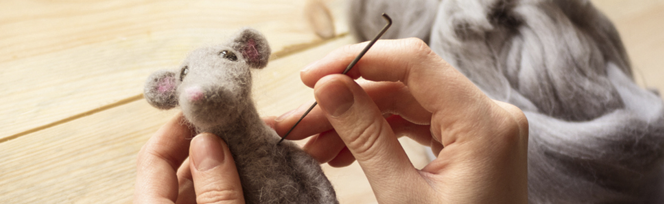 Close up of a hand making a mouse with needle felting