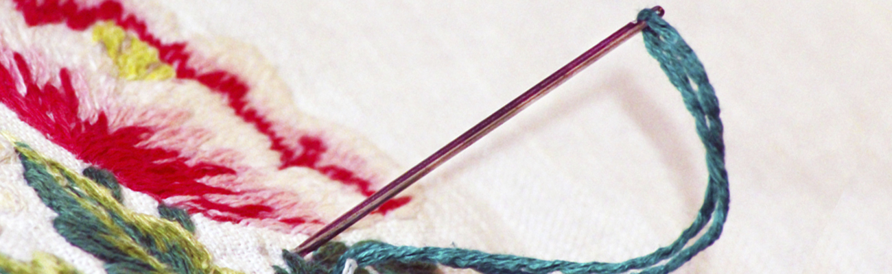 A close up of a needle making an embroidery stitch