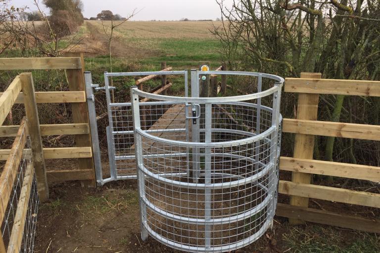 Steel kissing gate next to fence
