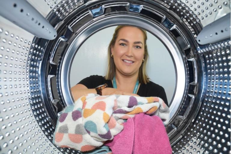 A city council colleague loading clothes into a washing machine.