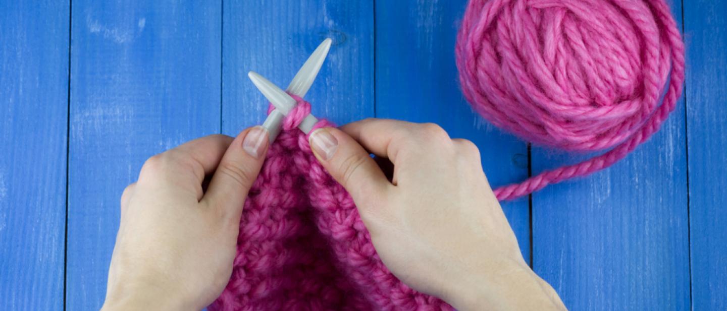 Hands knitting with bright pink wool