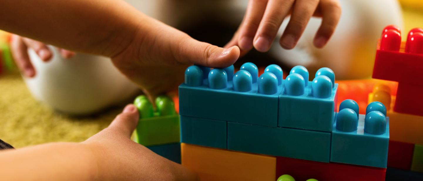 Children's hands reaching for building bricks