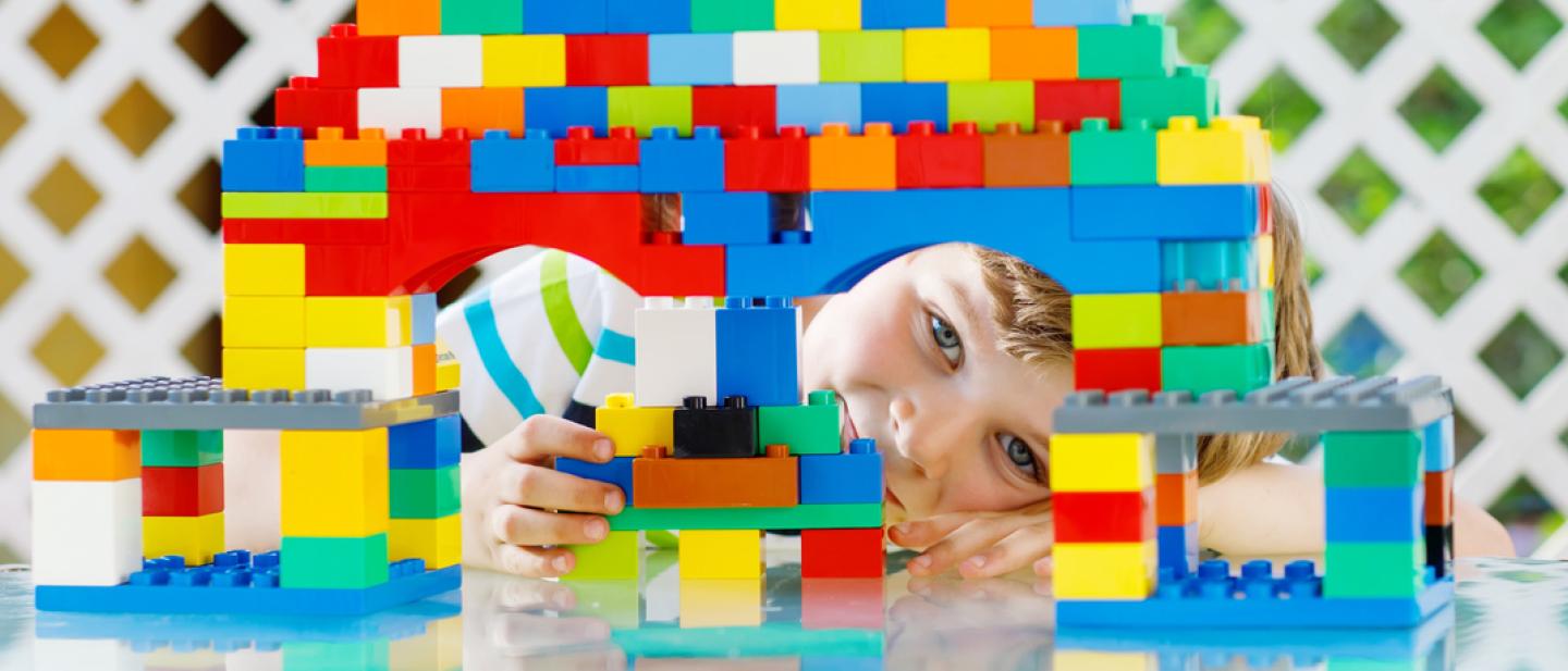 Boy peeking through a tower of building bricks