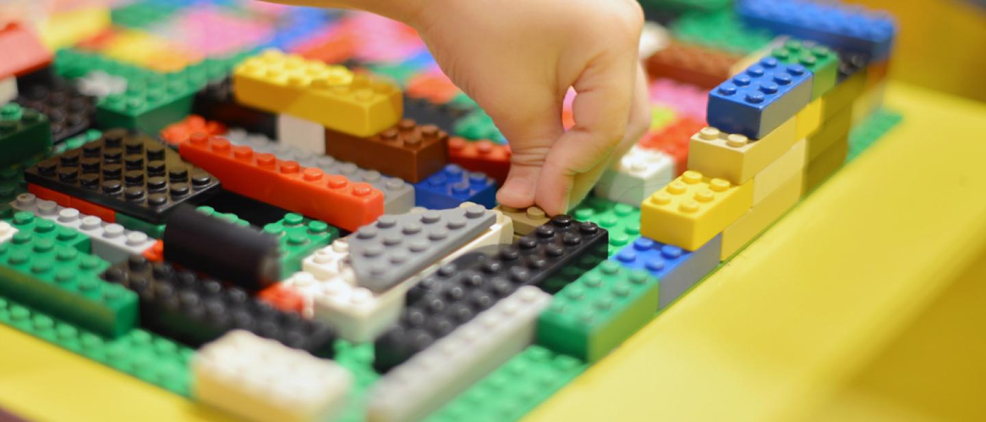 child's hand building with Lego blocks