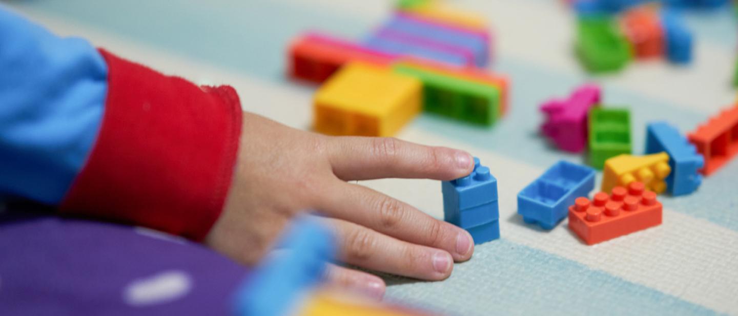 Child's hand playing with Lego bricks