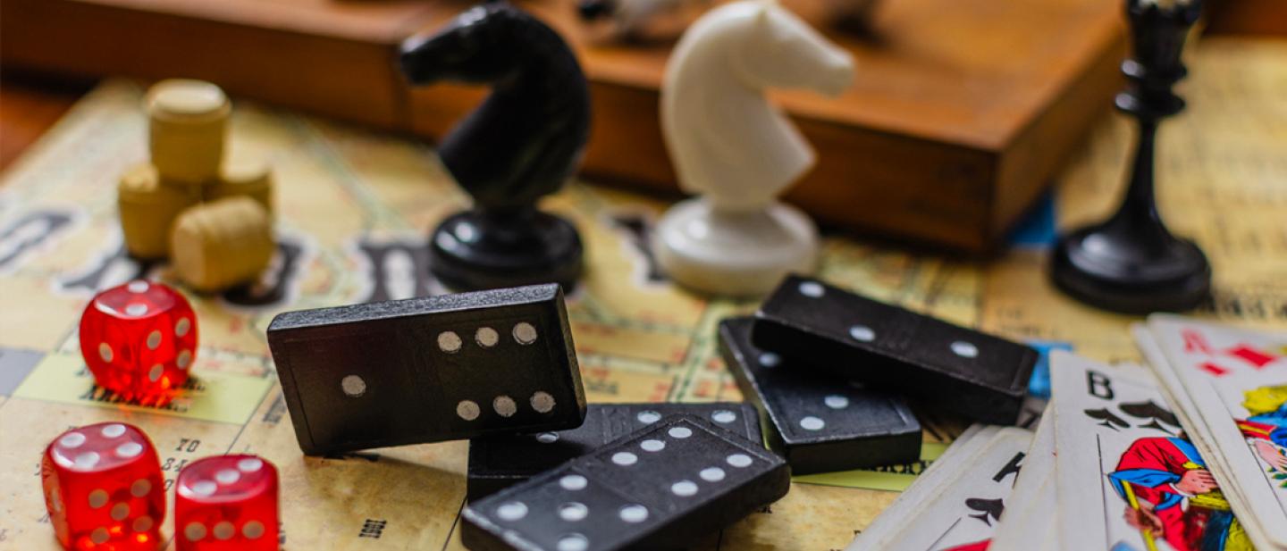Scattered chess pieces, dominoes, playing cards and dice.