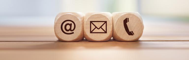 Three wooden blocks showing the symbols for @, email and phone