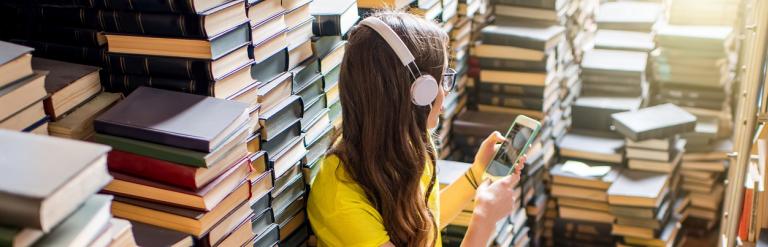Teenager listening with headphones in a room full of books