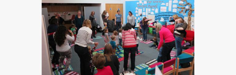 Photo of the children's area at Central Library hosting a music session with children and parents