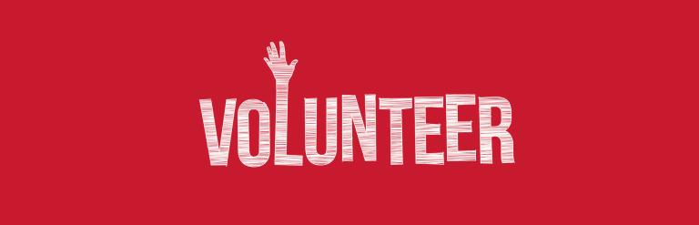 A red background with the word VOLUNTEER where a raised hand emerges from the top of the letter L.