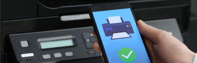 A printer in the background with a phone screen in the foreground showing a printer with a tick.