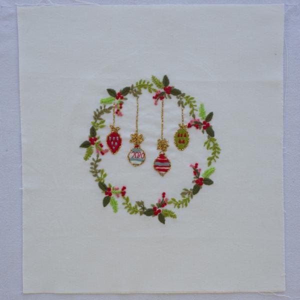Quilt square with an embroidered Christmas wreath and decorations with the year 2020 stitched onto it.