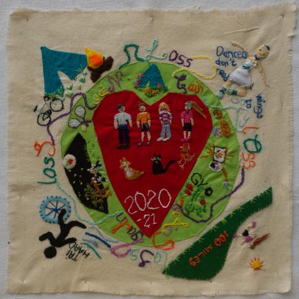 Quilt square using fabric and embroidery to make a scene of a globe with a big heart in the centre and people dancing, being together, running and other activities like camping and cycling. There is various text icluding "Dancers don't need wings to fly".