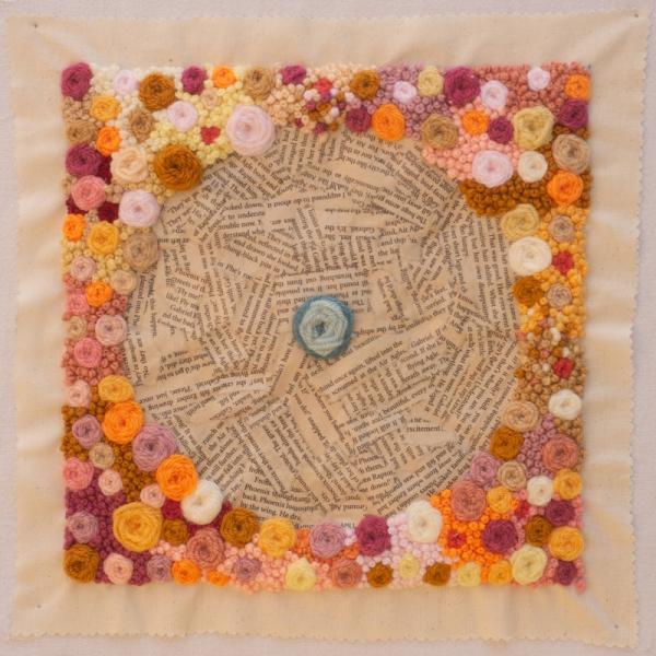 Quilt square  using print and wool to create a circle filled with text and a square frame of woollen balls and circles.