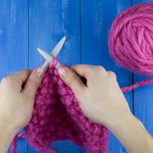 Hands knitting with bright pink wool