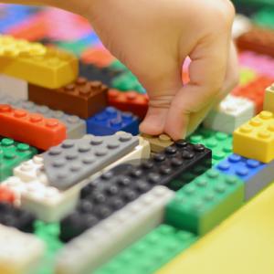 child's hand building with Lego blocks