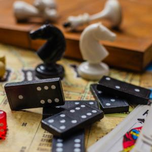 Scattered chess pieces, dominoes, playing cards and dice.